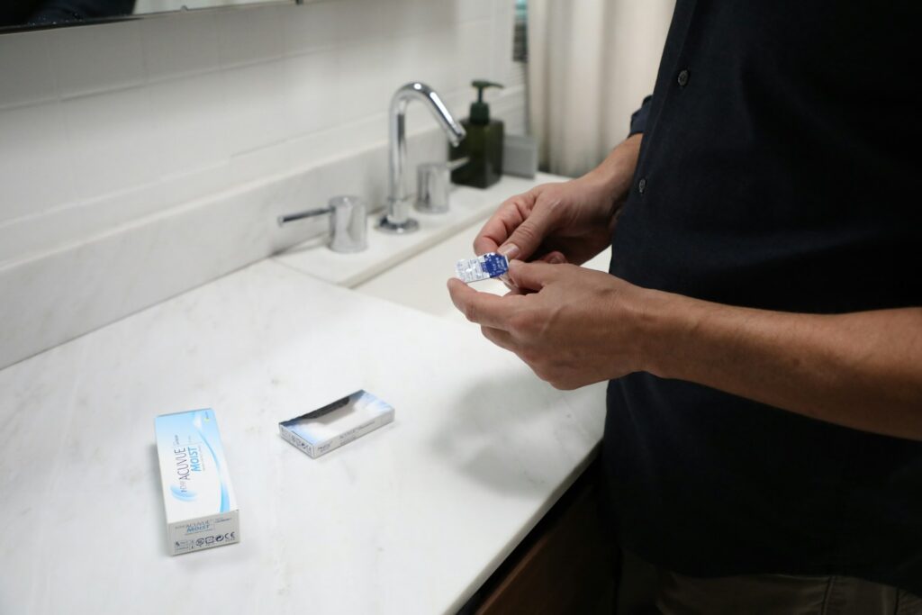 Person practicing contact lens hygiene by cleaning a lens case at the bathroom sink