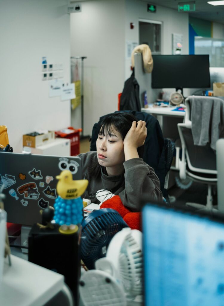 Woman rubbing tired eyes at her desk, illustrating the need for dry eye relief after long screen time