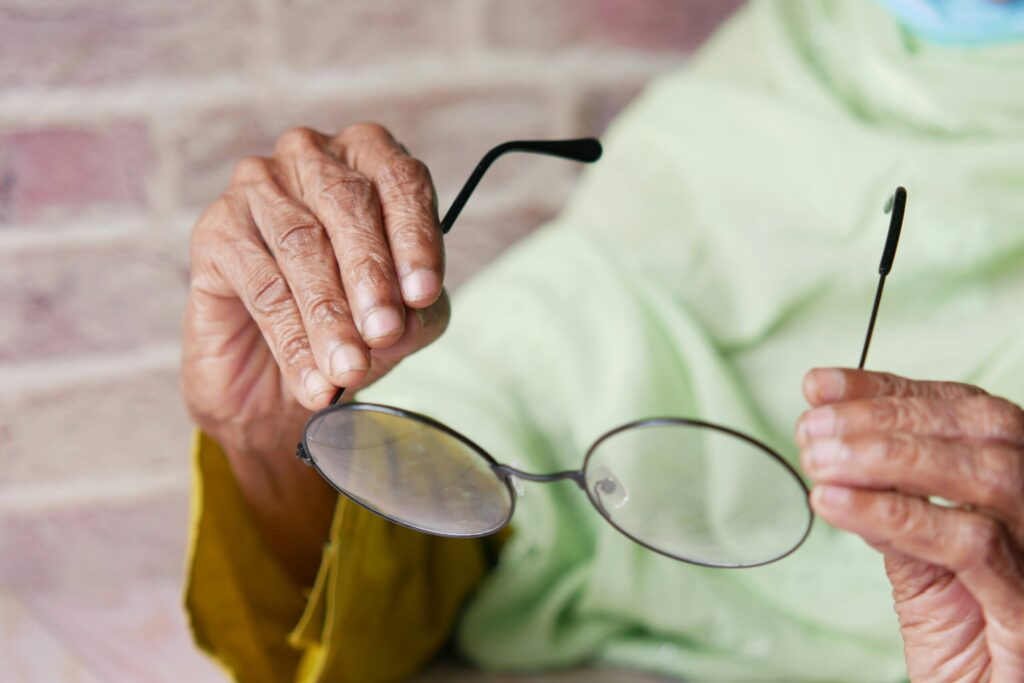 Older woman holding her glasses, a common moment for noticing early macular degeneration symptoms